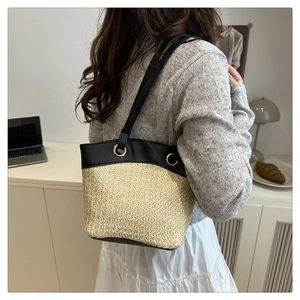 Detail of contrast stitch straw tote with black leather trim and gold metal rings