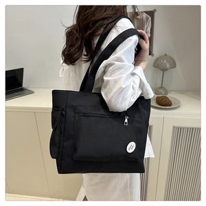 Detail view of a black large-capacity tote bag showing front zipper pocket and side pouch