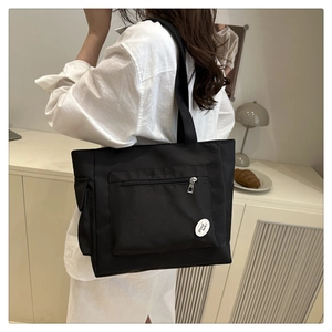 Détail du sac cabas en toile noire avec poche zippée et étiquette Good Luck brodée