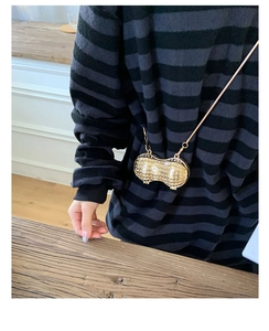 Detailed macro view of peanut-shaped gold metal mini bag with sparkling rhinestones