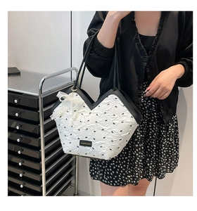 Detail view of large tote bag with embossed bow texture and elegant lace pearl pendant