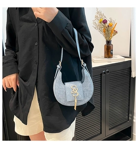 Bolso Hobo azul claro con logo SS dorado y borla llevado por una modelo de moda
