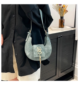 Detalle de bolso medialuna con borlas metálicas y textura de cuero PU retro elegante