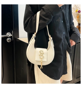 Detalle del bolso hobo blanco en forma de luna con logo dorado y borla metálica