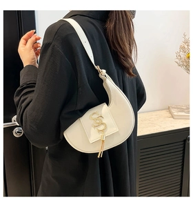 Detalle del bolso de media luna con broche dorado en S y adorno de flecos elegantes