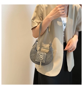 Detalle del bolso de media luna gris con textura de piel PU y borla metálica dorada