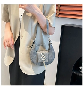 Detalle del bolso medialuna gris con textura de PU y logotipo con borla metálica
