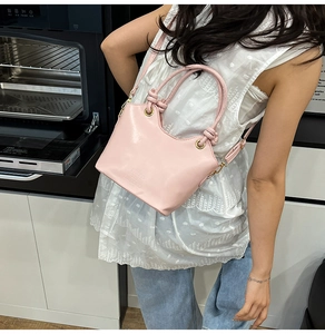 Dettaglio della borsa a secchiello rosa alla moda con manico a nodo e tracolla