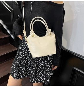 Dettaglio borsa a secchiello in pelle bianco crema con manico a nodo e logo