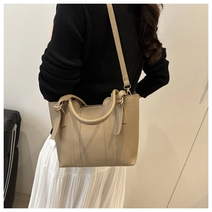 Detail of minimalist khaki bucket bag with lychee leather texture and gold hardware