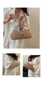 Detail view of apricot leather underarm bag with a decorative metal bow clasp