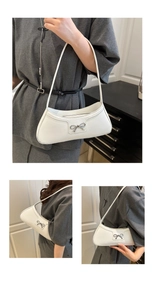 Detail view of white crescent baguette bag with silver bow accent and slim shoulder strap