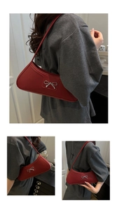Detail of the silver metal bow ornament on a red leather-textured underarm shoulder bag