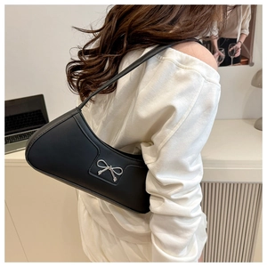 Detailed view of black leather underarm bag featuring a silver metal bow buckle accent