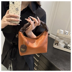 Detail of caramel pleated handbag with cloud-shaped handle and textured leather finish