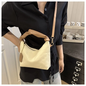 Detail of cream pleated shoulder bag with brown padded handles and gold metallic clips