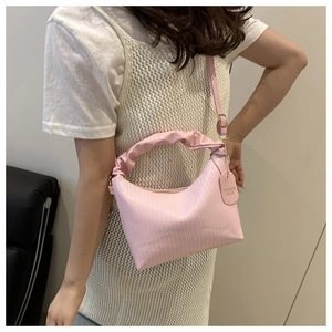 Detail of light pink shoulder bag featuring vertical pleated texture and ruffled handle