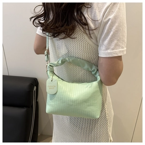 Detail of mint green pleated handbag with vertical stripe texture and fashion bag tag