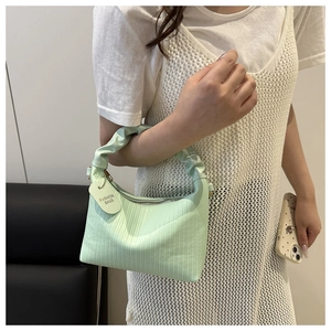 Detailed macro view of mint green pleated handbag with ruffles and silver zipper closure