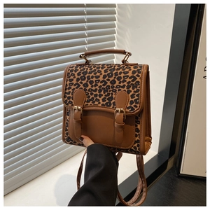 Detail of a vintage-style leopard print backpack with brown leather trim and metal buckles