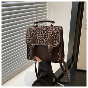 Close-up of leopard print backpack featuring vintage metal buckles and faux leather trim