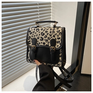 Detail of leopard print crossbody bag featuring black leather trim and double buckle closure