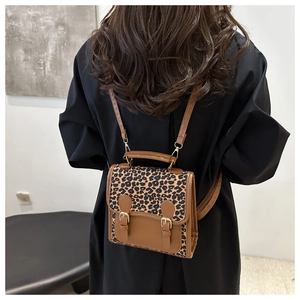 Detailed back view of a mini leopard print backpack with brown leather trim on a model