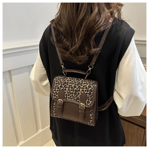 Detail of leopard print backpack with faux leather trim and decorative metal buckles