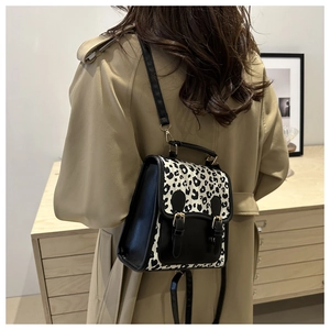 Detail of leopard print patchwork backpack showing the shoulder strap and texture on a trench coat