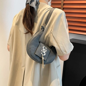 Bolso de hombro tipo media luna en PU gris oscuro con logo metálico y borla