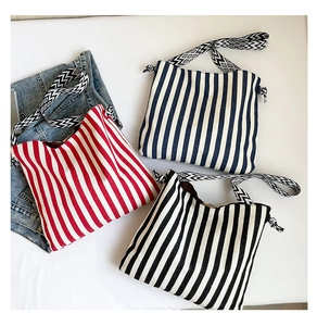 Detailed flat lay of striped canvas tote bags in red blue and black with woven straps