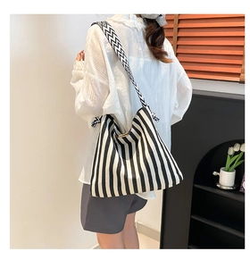 Detail of black and white striped canvas tote bag with geometric wide shoulder strap