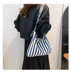Rear view of a model wearing a large blue striped canvas tote bag with a geometric strap