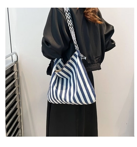 Detail of blue and white striped canvas tote bag with a wide geometric shoulder strap