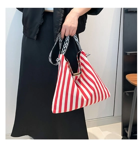 Detail of red and white striped tote bag with chevron pattern woven handle held by hand