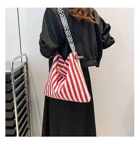 Detail of large canvas tote bag with red and white stripes and geometric woven strap