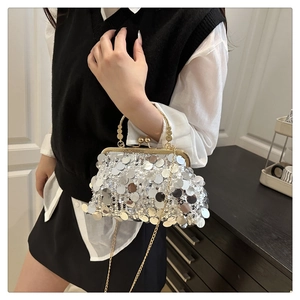 Macro detail of silver sequin evening bag with gold metal handle and chain strap