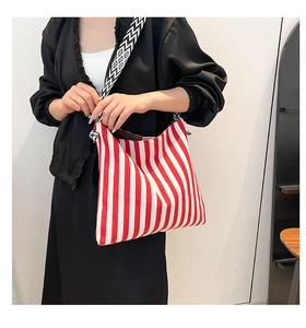 Detail of red and white striped canvas tote bag with woven geometric shoulder strap