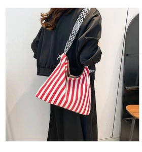 Detail of red and white striped hobo bag featuring a geometric woven wide shoulder strap