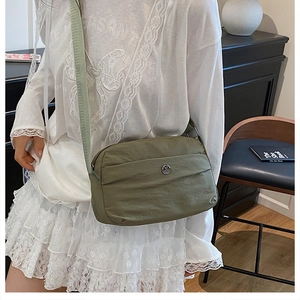 Detailed view of dark green nylon crossbody bag with metallic M logo and pleat design