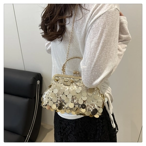 Sac à main doré à paillettes avec poignée métallique et longue chaîne sur un modèle