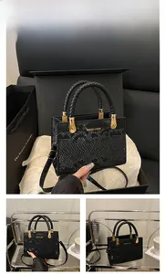 Close-up of black snakeskin tote bag with leather handles and gold metal hardware