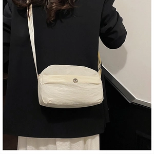 Close-up shot of a minimalist cream nylon crossbody bag for women's daily use.
