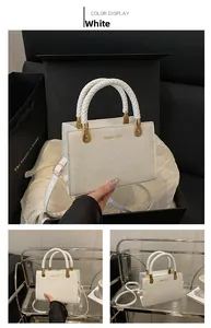 Detail of white PU leather handbag with woven handle and gold hardware in luxury setting