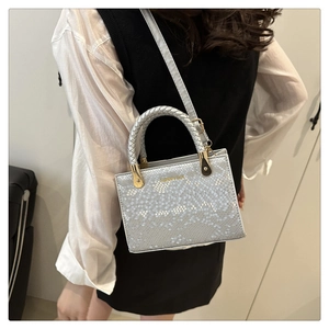 Detailed view of snake texture handbag with woven handle and gold hardware accents