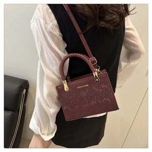 Detail der burgunderroten Handtasche mit Schlangenhaut-Textur und gewebtem Griff