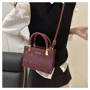 Close-up of wine red crossbody bag featuring crocodile texture and woven handles