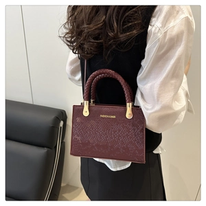 Detail of dark wine red snake pattern embossed leather handbag with woven handles