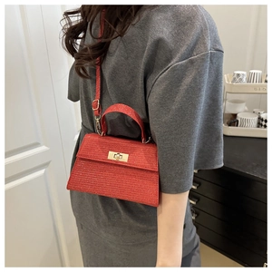 Detail of red sequined handbag with metal turn-lock closure worn by a model