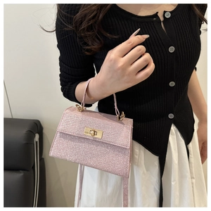 Detail of pink glitter square handbag featuring gold hardware and shiny texture